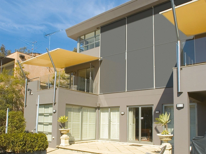 Un maison avec deux stores bannes jaunes et un store gris.